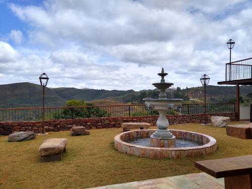 a fountain in the middle of a yard with benches at Hotel Recanto do Ouro in Ouro Preto
