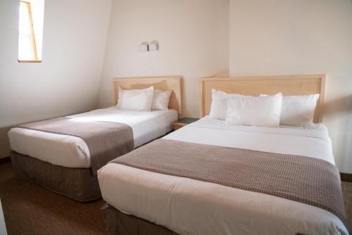 a hotel room with two beds with white sheets at Rocky Mountain Ski Lodge in Canmore