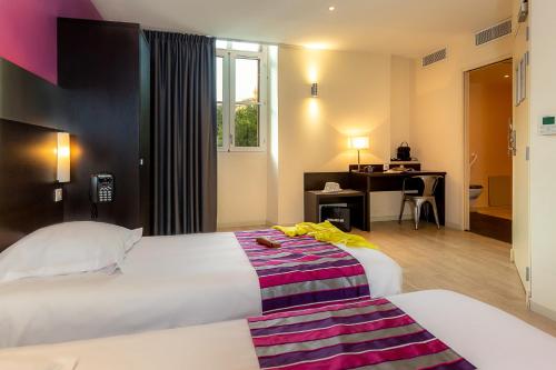 マルセイユにあるホテル ターミヌス サン シャルルのベッド2台とデスクが備わるホテルルームです。