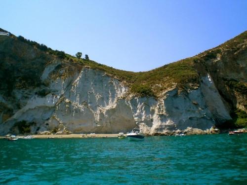 a boat sitting on the water next to a cliff at La Maison Galu' in Itri