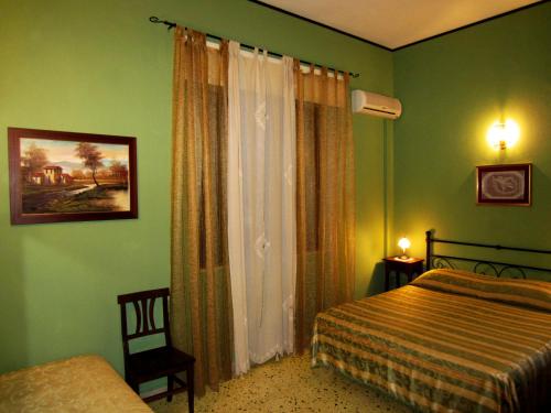 una camera da letto con pareti verdi, un letto e una finestra di Xanadu - Villa Giardinata a Valderice