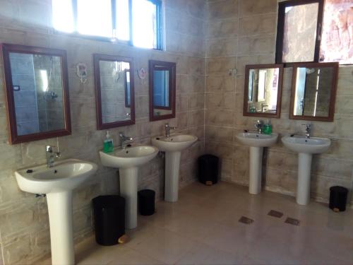 a bathroom with three sinks and two mirrors at Wadi Rum Caravan Camp in Wadi Rum