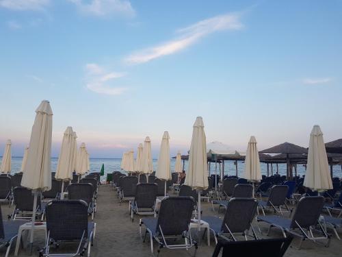 a row of chairs and umbrellas on a beach at Frideriki Apartments in Olympiaki Akti