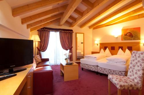 a hotel room with two beds and a flat screen tv at Hotel Rotwand in Laives