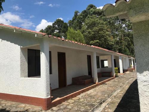 a white building with trees in the background at FINCA EL RECUERDO in Gachetá