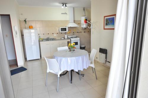 eine Küche mit einem Tisch mit weißen Stühlen und einem Kühlschrank in der Unterkunft NorthBeach ::: Dpto. 7 in Colón
