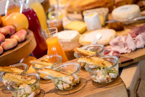 a table topped with glasses of food and cheese at Hôtel Restaurant Gastronomique La Huchette in Mâcon