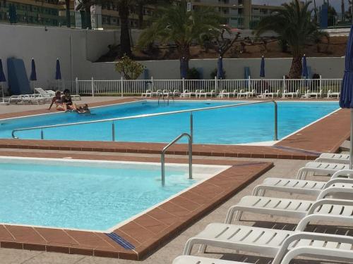 una gran piscina con sillas blancas en un hotel en 5 min walk from Yumbo! 417, en Playa del Inglés