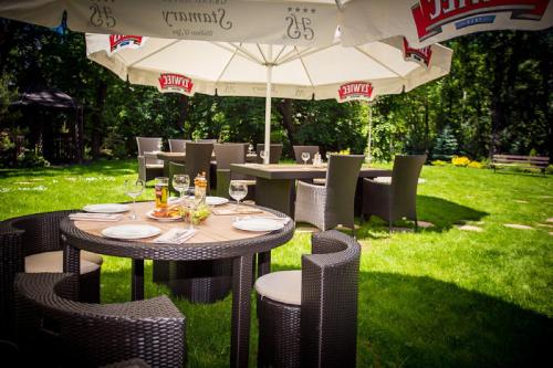 a table with chairs and an umbrella in the grass at Grand Hotel Stamary in Zakopane