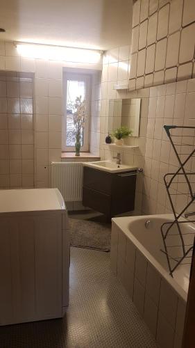 a white bathroom with a tub and a sink at Pension Moserhaus in Harburg