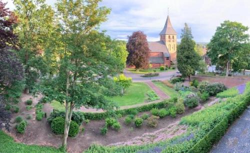 an aerial view of a garden with a church in the background at Burg Wassenberg in Wassenberg