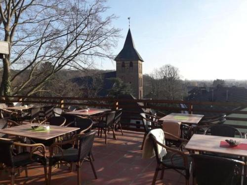 an outdoor patio with tables and chairs and a clock tower at Burg Wassenberg in Wassenberg