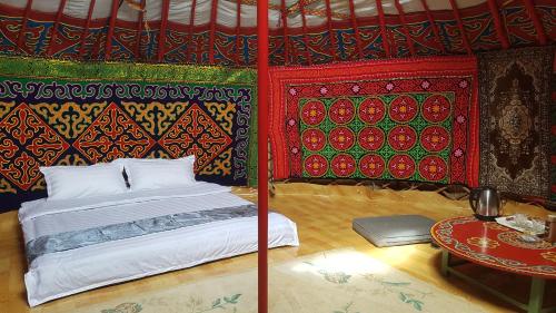 a bed in a room with colorful walls and a table at Ger ,Bulbul Jamak travel in Ölgiy