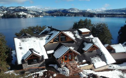a house on a lake with snow covered roofs at Amarras in Villa Pehuenia