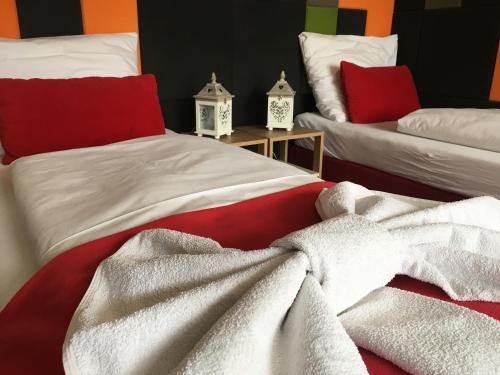 a bedroom with two beds with white blankets and red pillows at Apartamenty Lawenda in Rabka