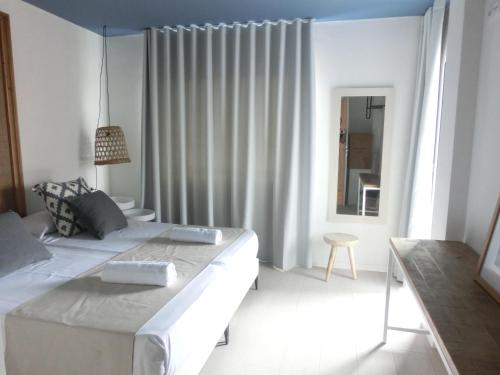 a white bedroom with a large bed and a mirror at YOU & CO. Saler Beach Boutique in Valencia