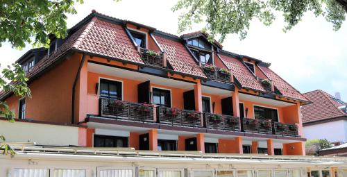 pomarańczowo-biały budynek z dachem w obiekcie Seehotel Pegasus w mieście Herrsching am Ammersee