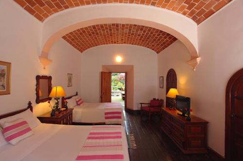 a hotel room with two beds and a tv at Posada del Tepozteco - Hotel & Gallery in Tepoztlán