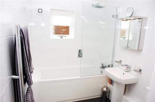 a white bathroom with a sink and a shower at Flat 4 Summertown Court in Oxford