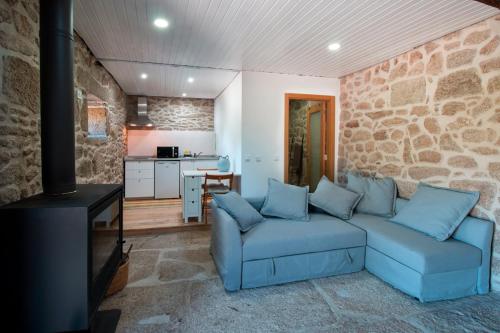 a living room with a blue couch and a stone wall at Casa da Mina in Carapito