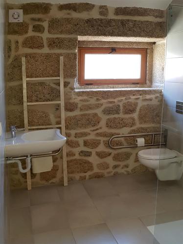 a bathroom with a sink and a toilet and a window at Casa da Mina in Carapito