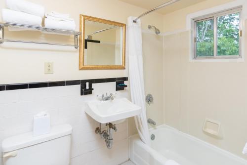 a bathroom with a sink and a toilet and a mirror at Ocean Park Inn Cape Cod in Eastham