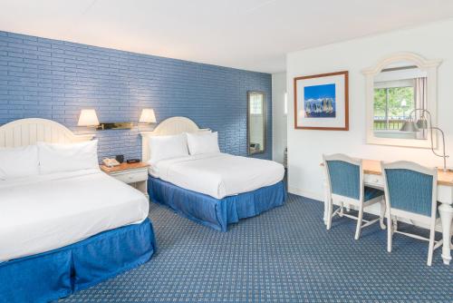 Cette chambre d'hôtel comprend deux lits, une table et des chaises. dans l'établissement Ocean Park Inn Cape Cod, à Eastham