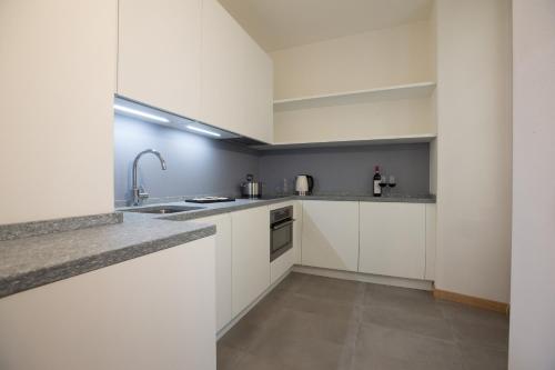 a kitchen with white cabinets and a sink at HOTEL AD Residence in Bormio