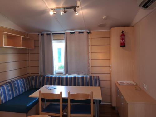 ein Wohnzimmer mit einem Sofa, einem Tisch und Stühlen in der Unterkunft Mobil home climatisé en Alsace in Biesheim