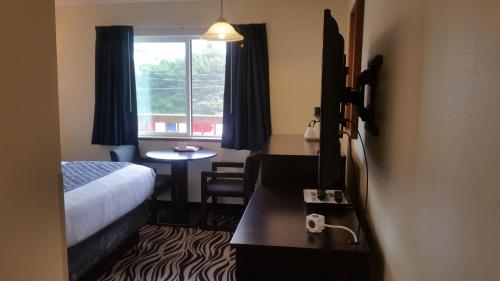 a hotel room with a bed and a table and a window at Tradewinds Motel in Rockaway Beach