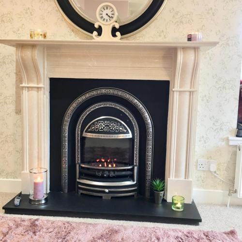 a fireplace with a black mantle with a fire place at The Little Beech Tree in Linlithgow