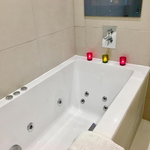 a white bath tub in a bathroom with red candles at The Little Beech Tree in Linlithgow