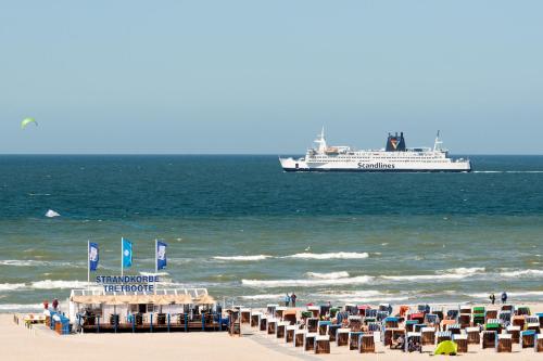 a cruise ship in the ocean with chairs and a beach at Strand-Hotel Hübner in Warnemünde