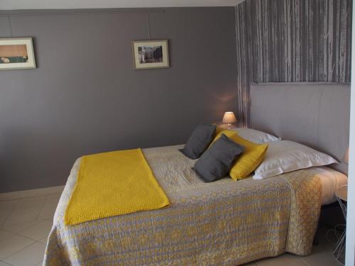Une Heure Bleue في مانوسك: غرفة نوم عليها سرير مع بطانية صفراء