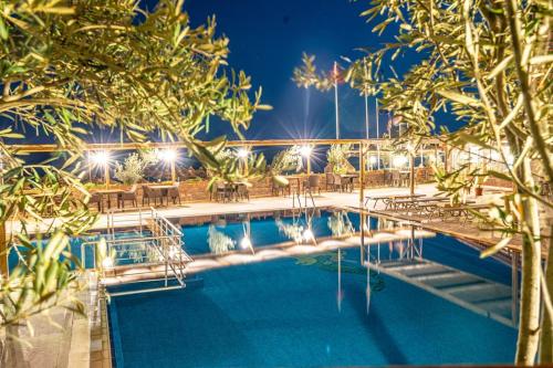 a swimming pool with tables and chairs at night at Tas Otel 17 in Behramkale
