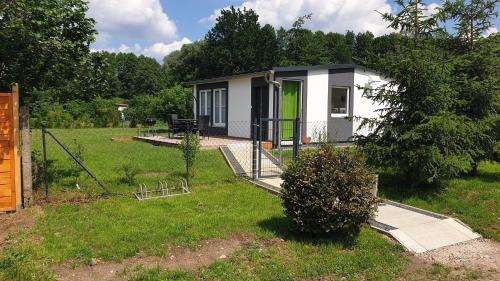 a small white house with a green door in a yard at Kranichnest in Rheinsberg