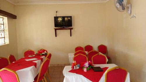a room with two tables and red chairs and a television at Kanberra Hotel in Lira