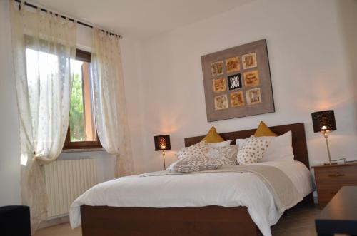 a bedroom with a bed with white sheets and a window at Villa Patrizia in Moncalvo