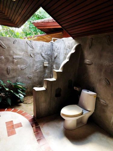 a bathroom with a toilet in a rock wall at Rachavadee Bankrut Resort in Ban Krut