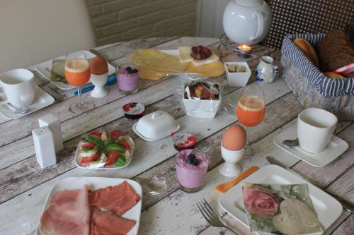 una mesa con platos de comida y vasos de zumo de naranja en Kerstins Bed and Breakfast, en Egmond aan Zee