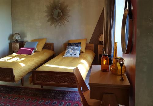a bedroom with two beds and a table and a mirror at les forges du lou in Jugon Les Lacs