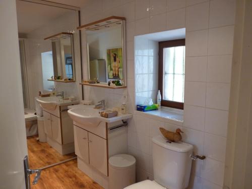 a bathroom with two sinks and a toilet and a mirror at Domaine de la Safranière - Chambre d'hote in Saint-Léger