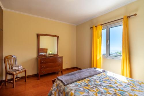 a bedroom with a bed and a dresser and a mirror at Madeira House in Calheta