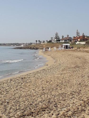 a sandy beach with the ocean and houses in the background at TAnoelvira in San Lorenzo
