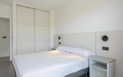 a white bedroom with a bed and a white headboard at Apartamentos Onzamar in Sanxenxo