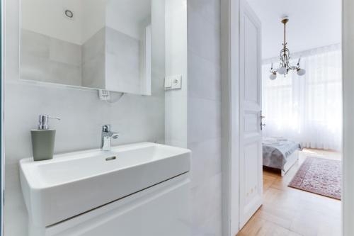 uma casa de banho branca com um lavatório e um quarto em The Dancing House Residence em Praga