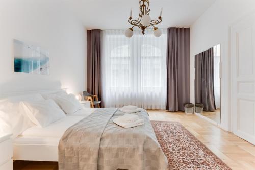 um quarto branco com uma cama e um lustre em The Dancing House Residence em Praga