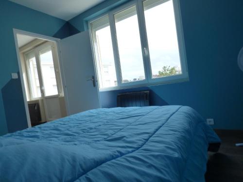 ein blaues Schlafzimmer mit einem Bett und zwei Fenstern in der Unterkunft Appartement Plein Sud in Berck-sur-Mer