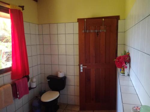 a bathroom with a toilet and a wooden door at Fidelito Ranch & Lodge in Tambor