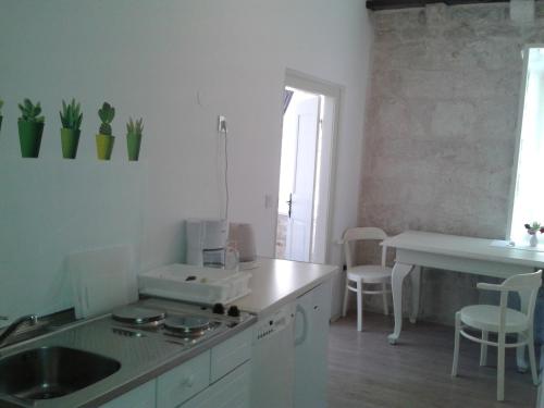 a white kitchen with a sink and a table at Apartments Milion in Korčula